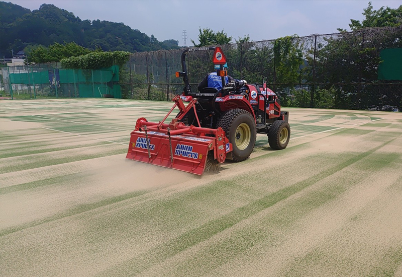ロータリアタッチメントで散布した硅砂を人工芝に刷り込み